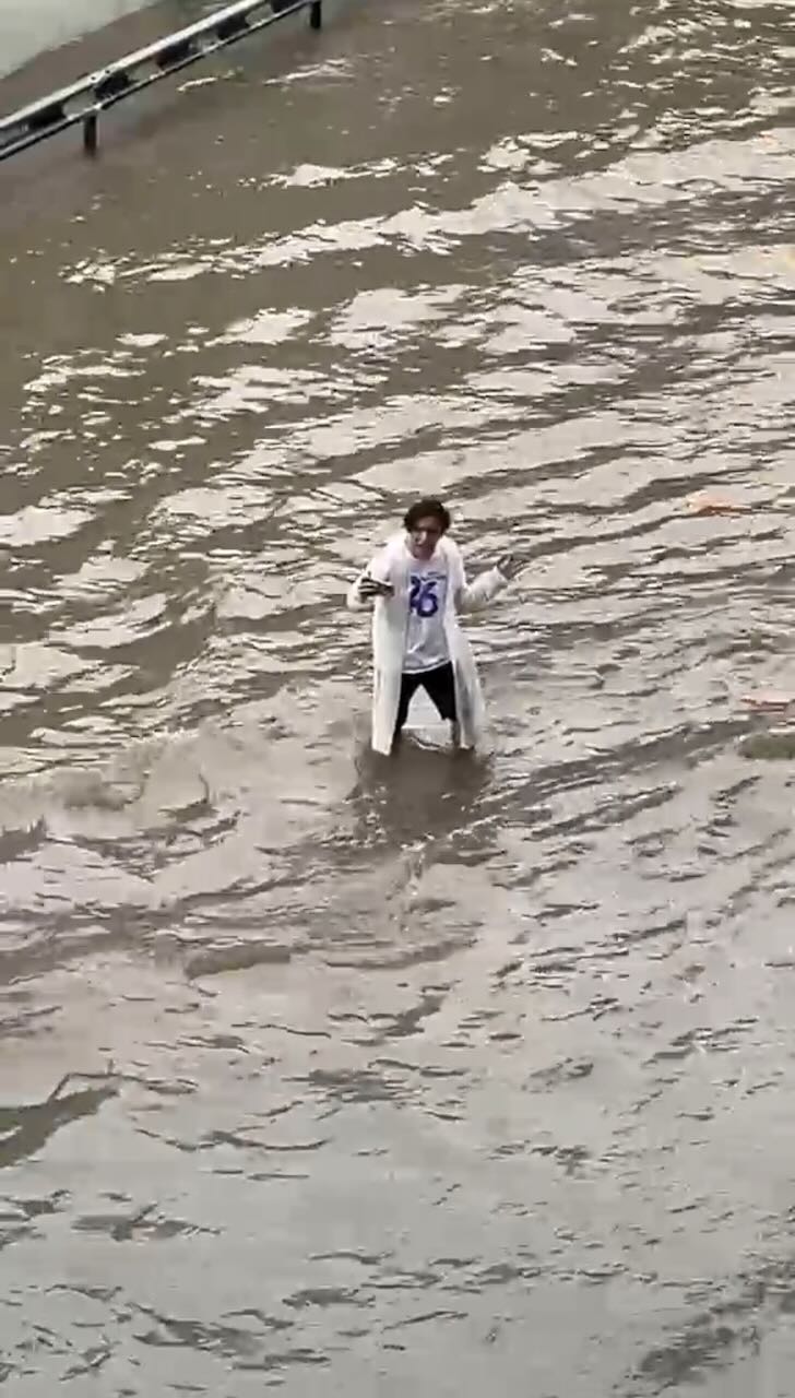 A dude recording a video while standing in the middle of a flooded road